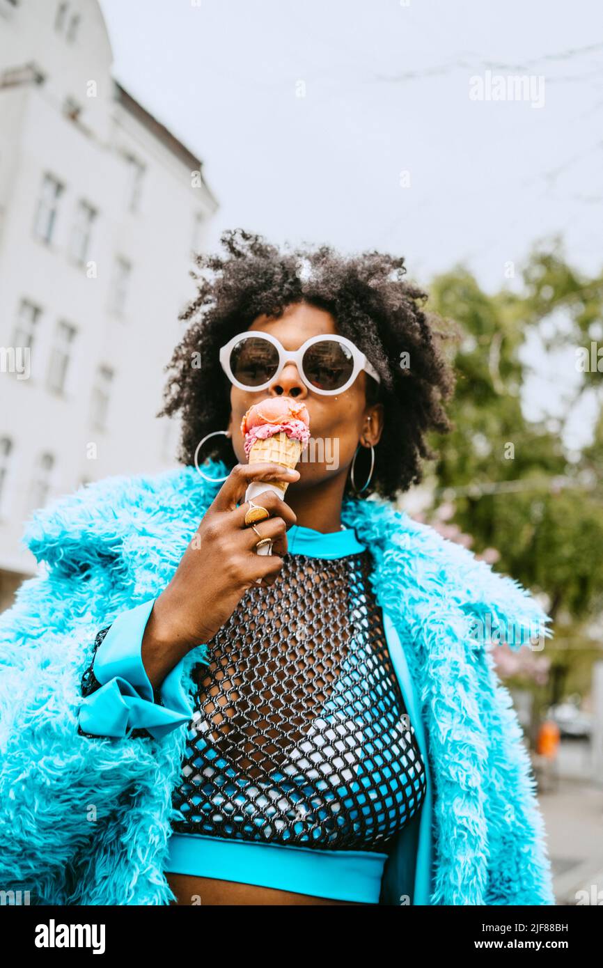 Young hipster woman with fur jacket eating ice cream Stock Photo