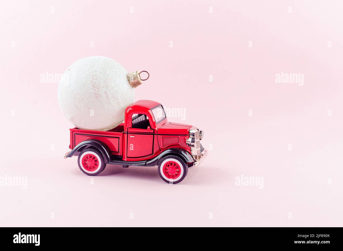 Red retro Pickup with Christmas decoration ball on pastel pink background. Merry Christmas holiday concept. copy space. Template of greeting card.Zapo Stock Photo