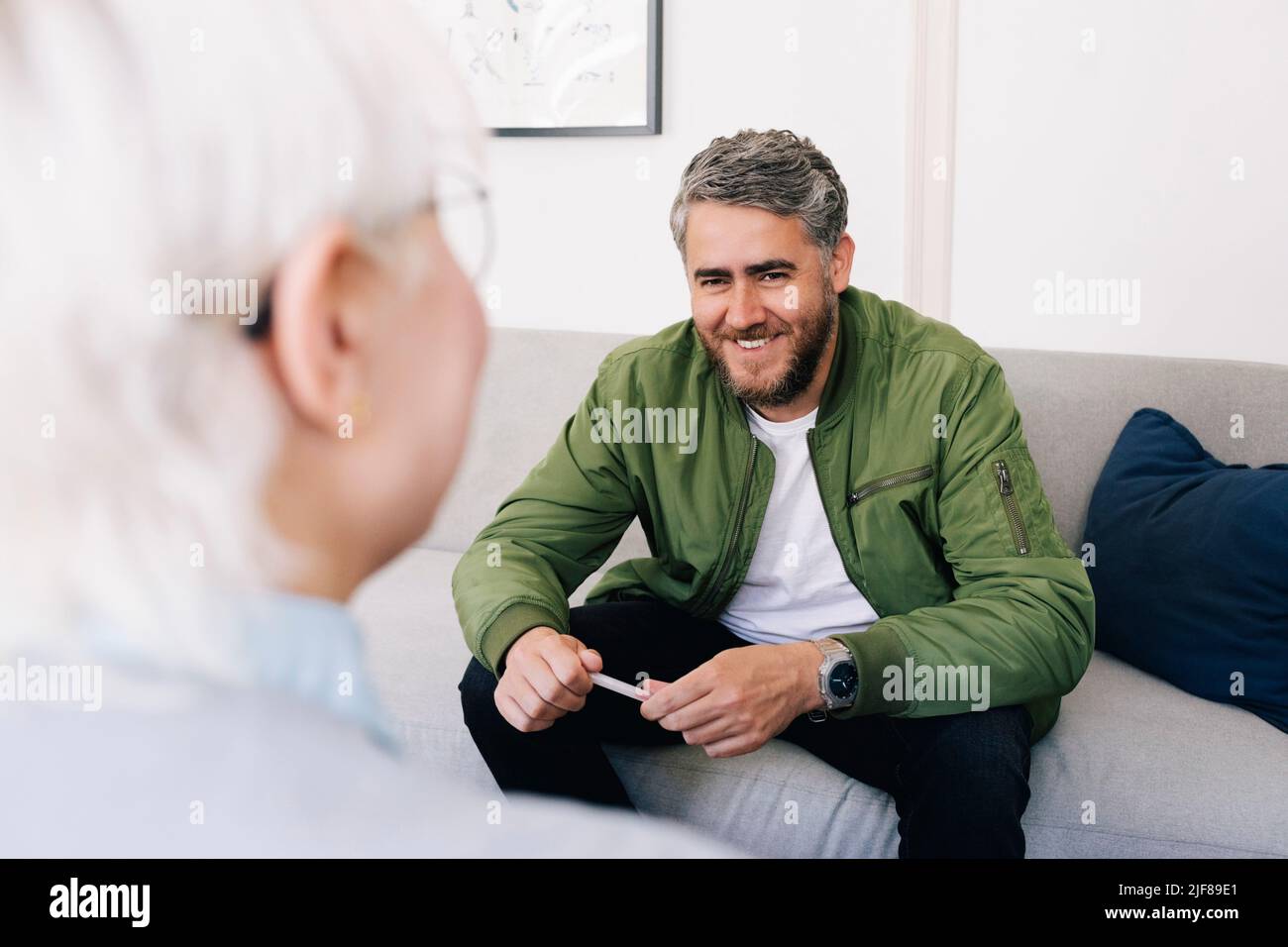 Smiling man talking with female psychotherapist in therapy office Stock Photo