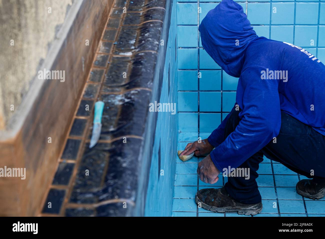 worker with sponge cleaning pool to apply grout between tiles Stock Photo Alamy