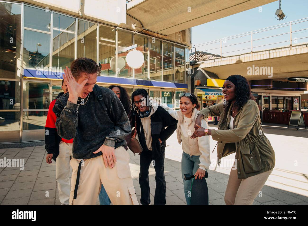 Multiracial friends cheering young man dancing at street Stock Photo