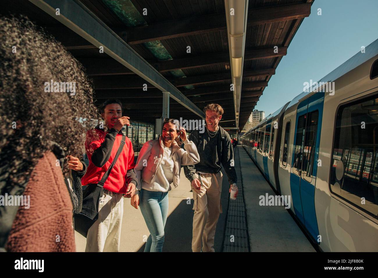 Multiracial playful friends standing near train at railroad station Stock Photo