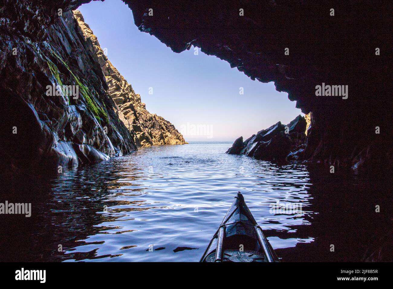 Sea kayaking in a sea cave off the Pembrokeshire Coast in Wales Stock Photo