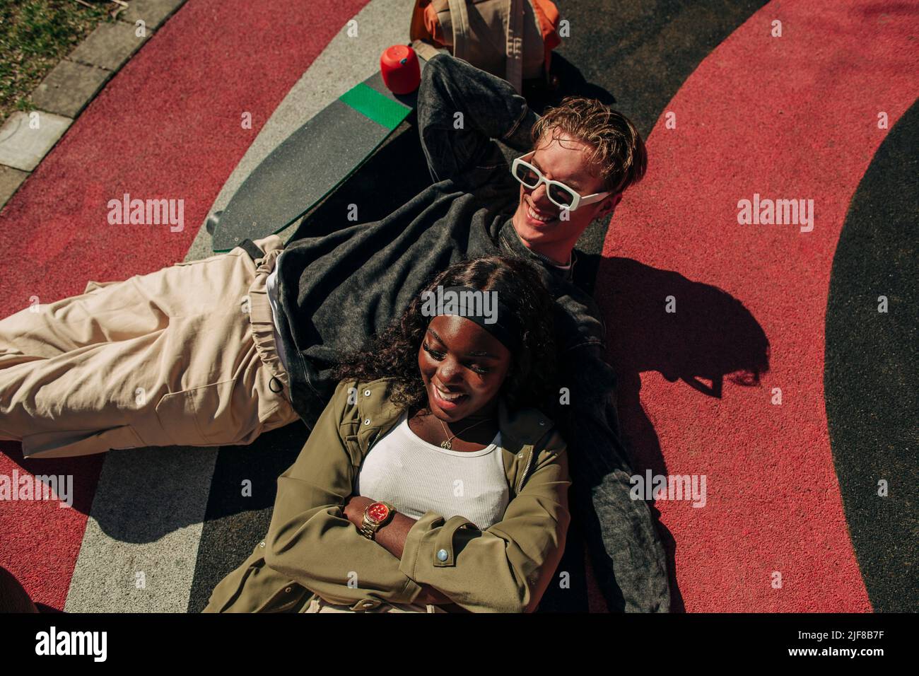 Multiracial young man and woman lying in playground on sunny day Stock Photo