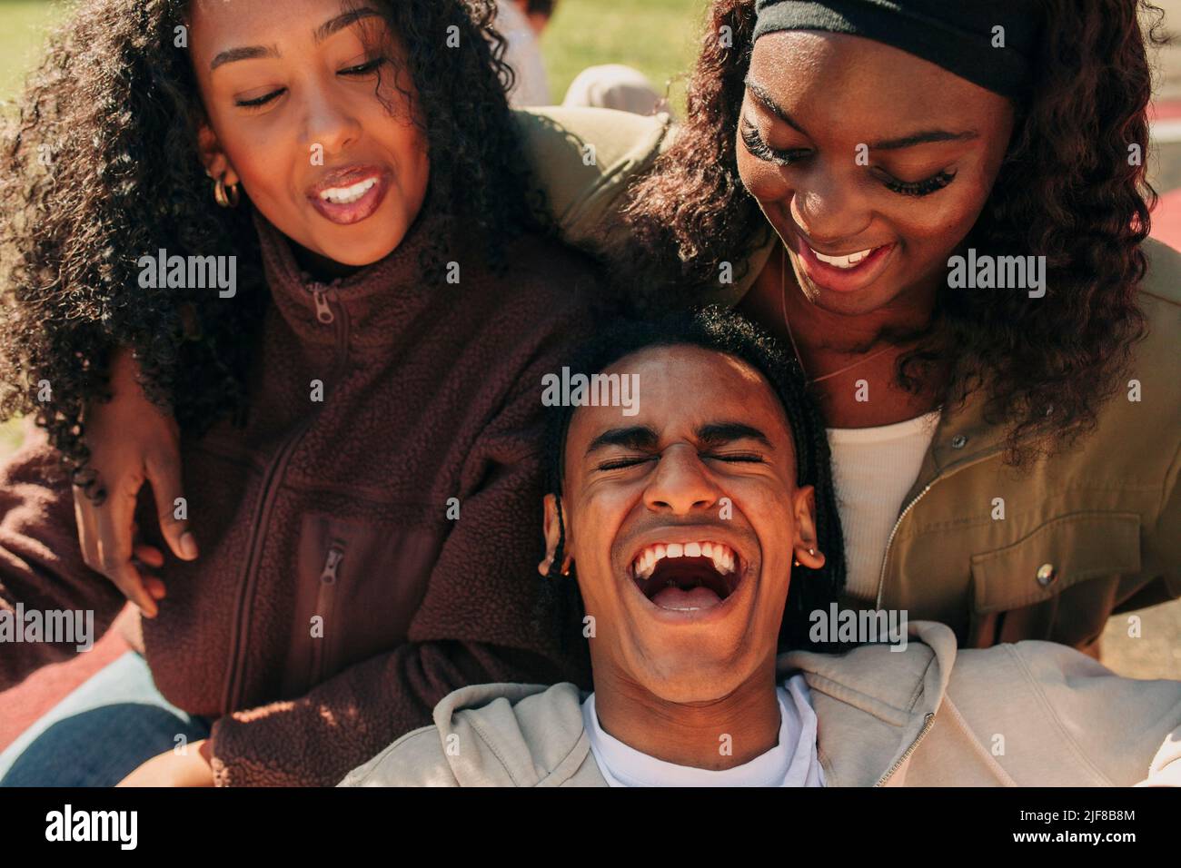 Young man laughing while leaning on female friends Stock Photo