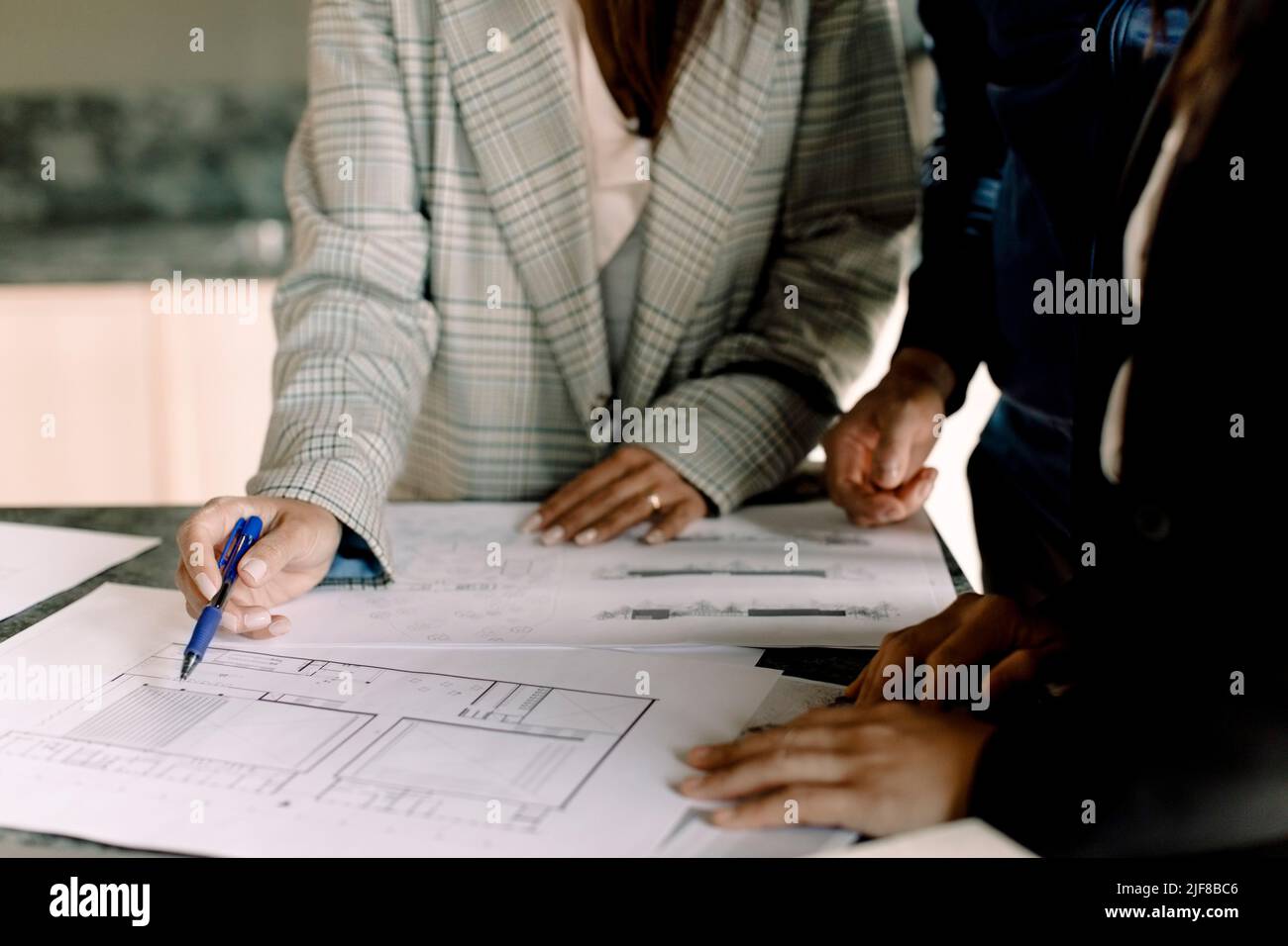 Midsection of real estate agent showing blueprint to customers Stock Photo