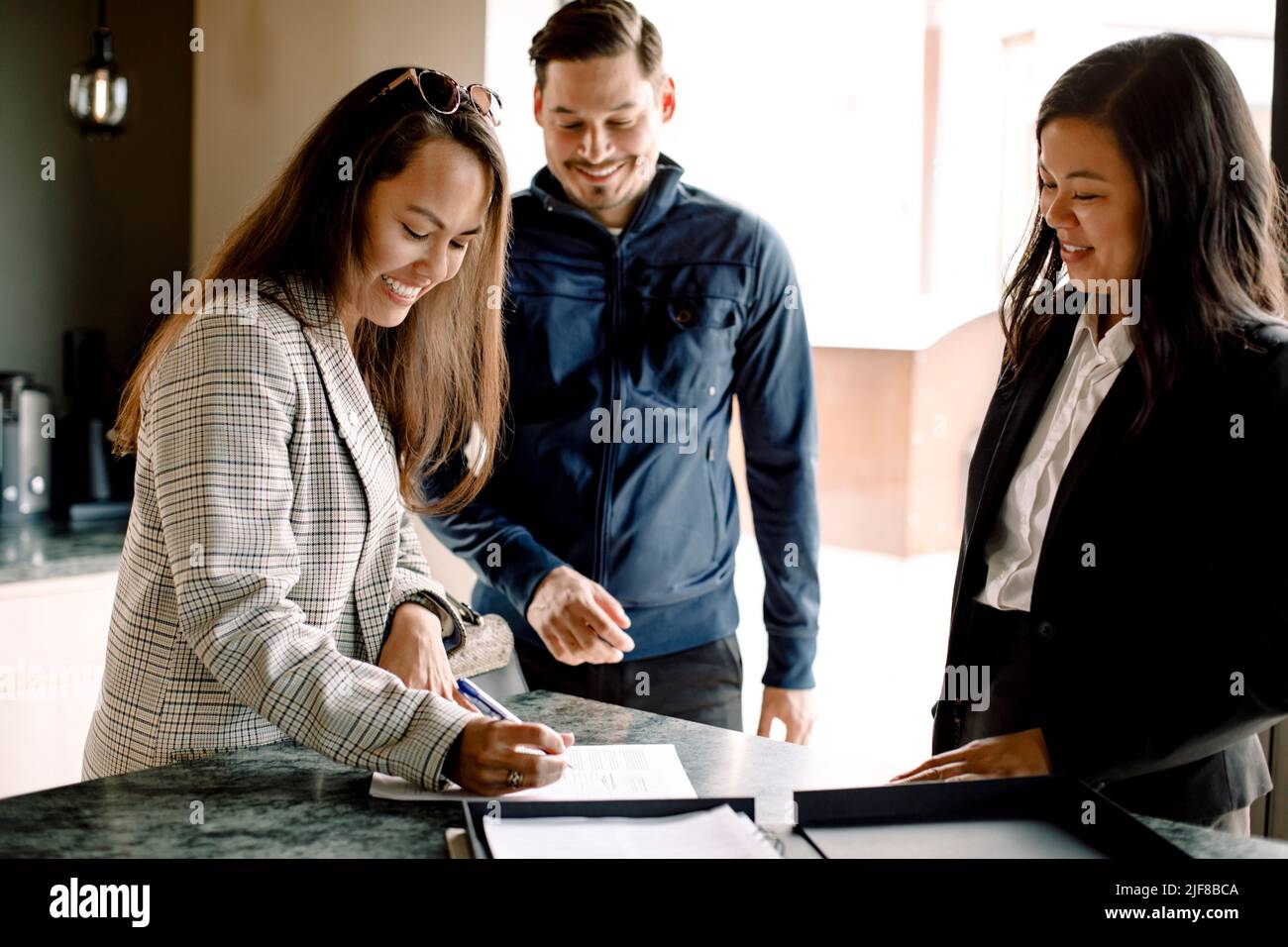 Couple signing contract with realtor at kitchen island of new house Stock Photo