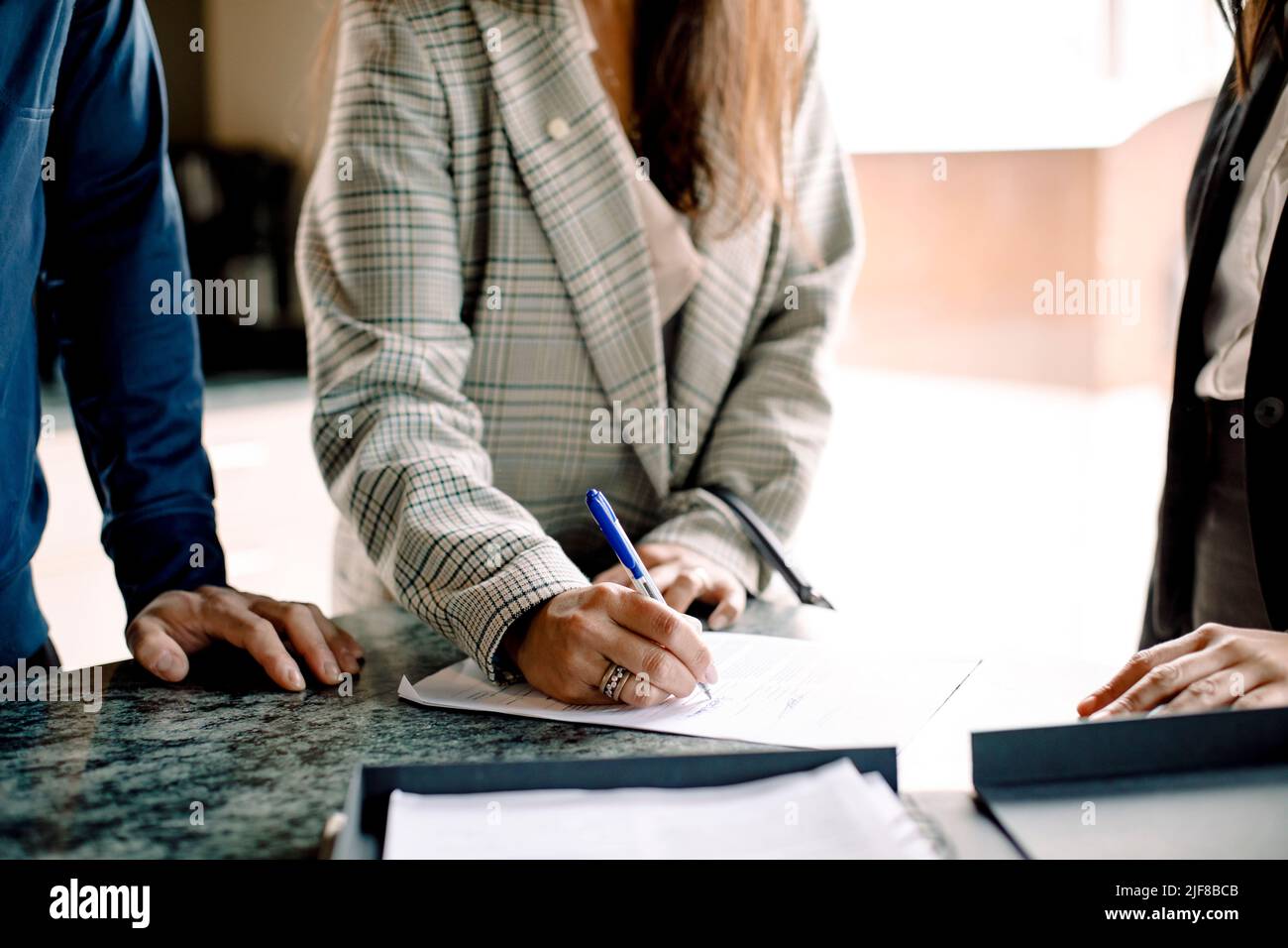 Midsection of couple signing contract with real estate agent in kitchen Stock Photo