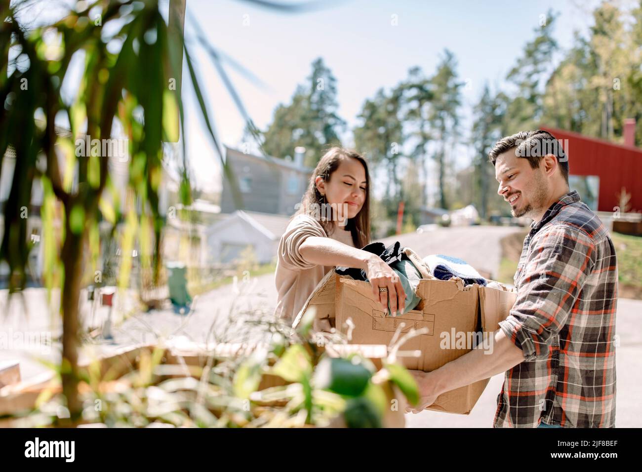 Couple carrying cardboard box during sunny day Stock Photo