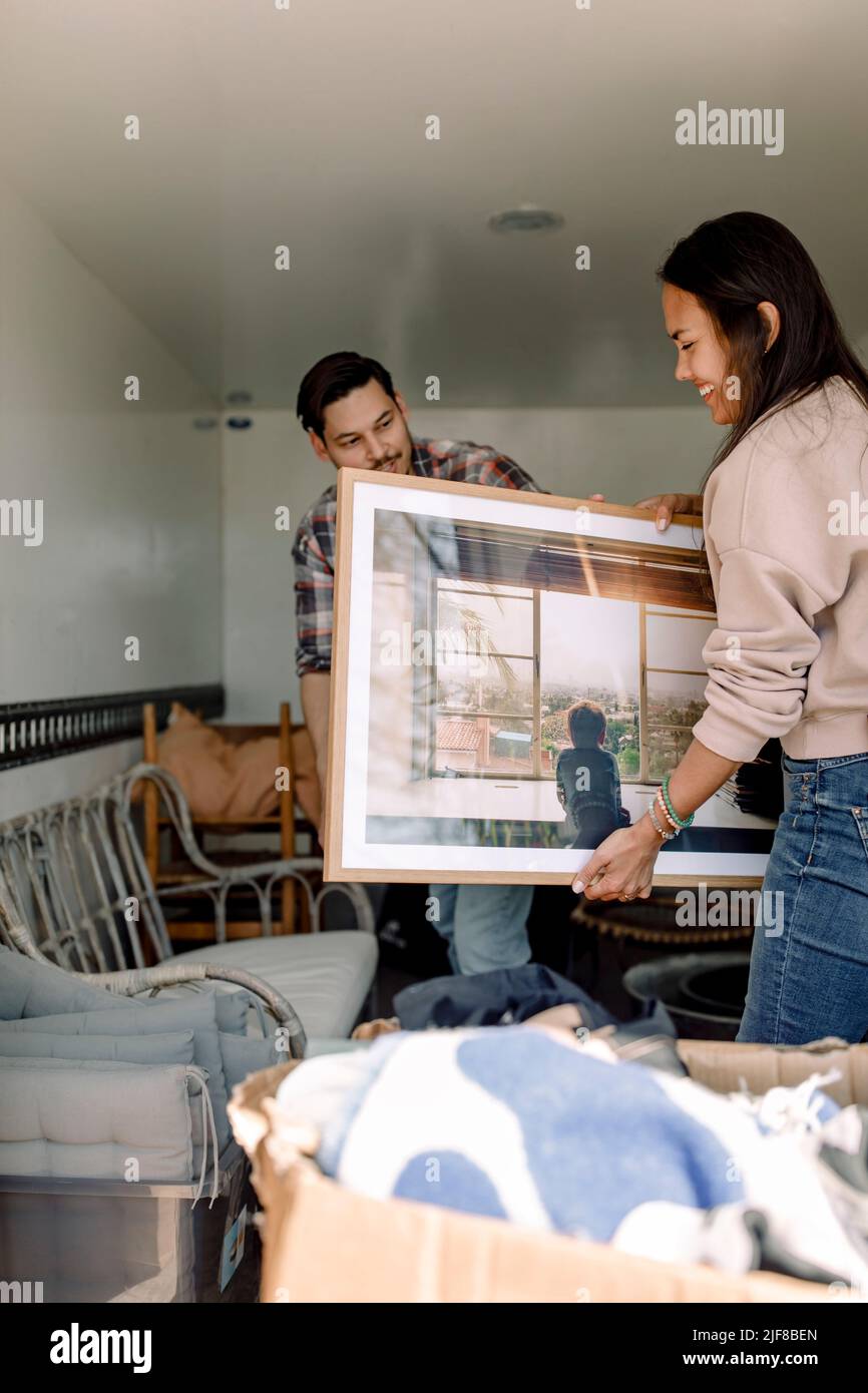 Couple unloading painting from truck while relocating in new house Stock Photo