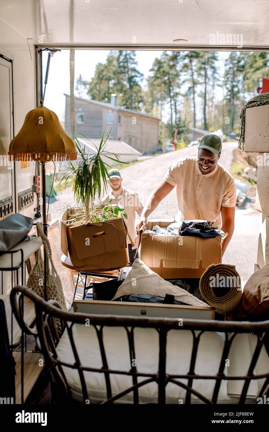 Multiracial delivery men picking cardboard boxes from truck Stock Photo