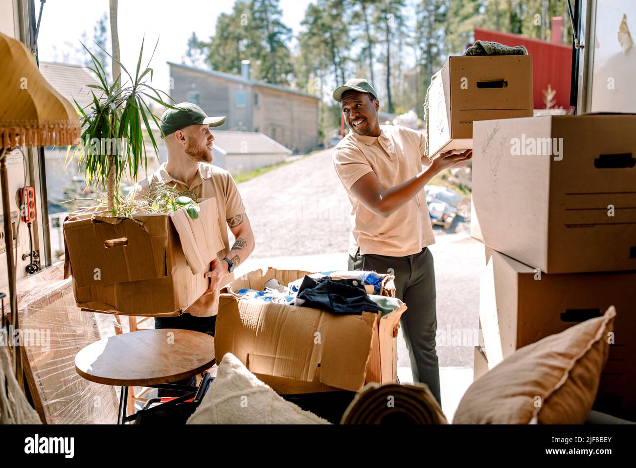 Multiracial movers unloading boxes from delivery truck Stock Photo