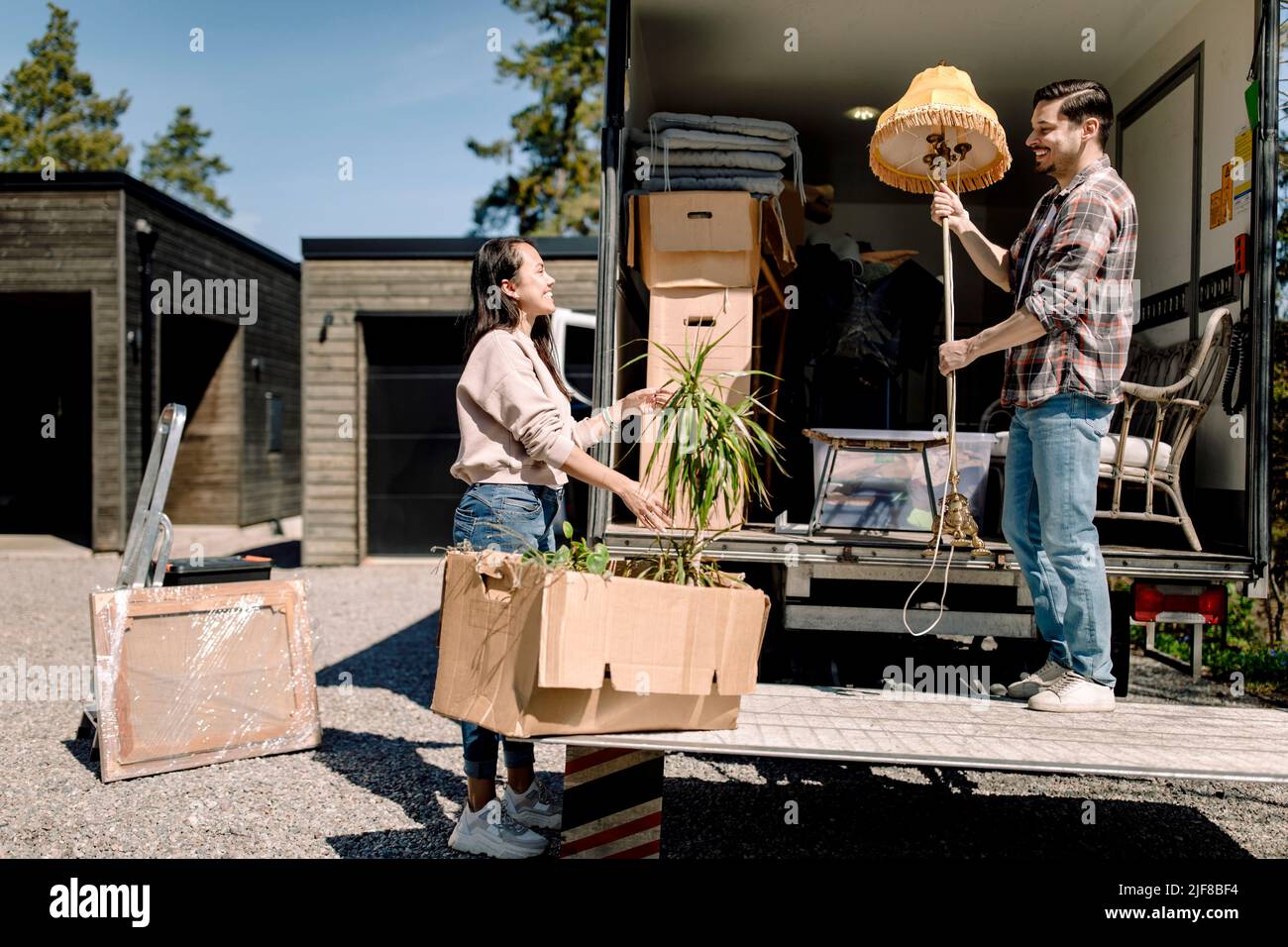 Couple unloading cardboard boxes from truck during sunny day Stock Photo