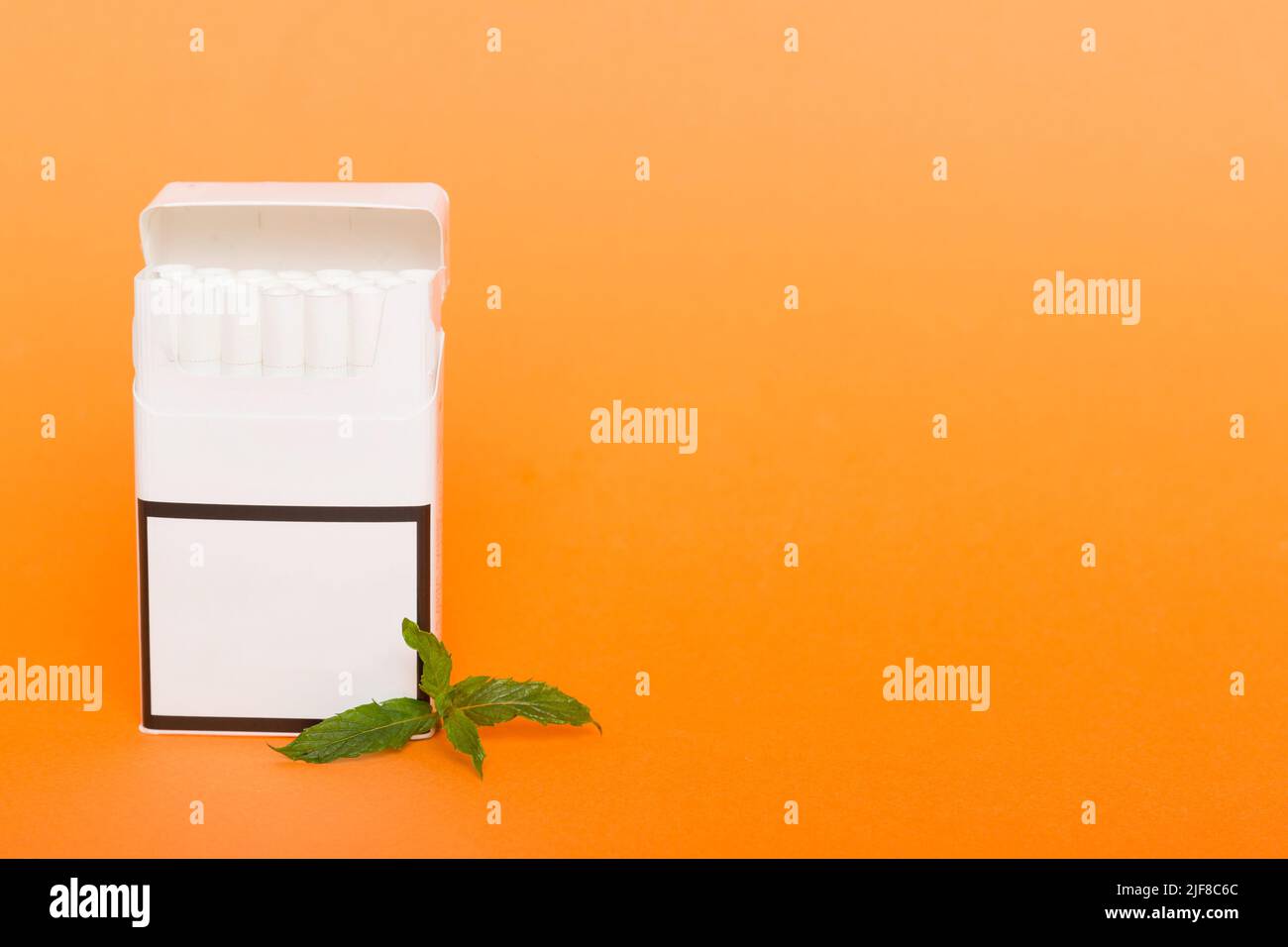 Pack of menthol cigarettes and fresh mint on colored table, Menthol