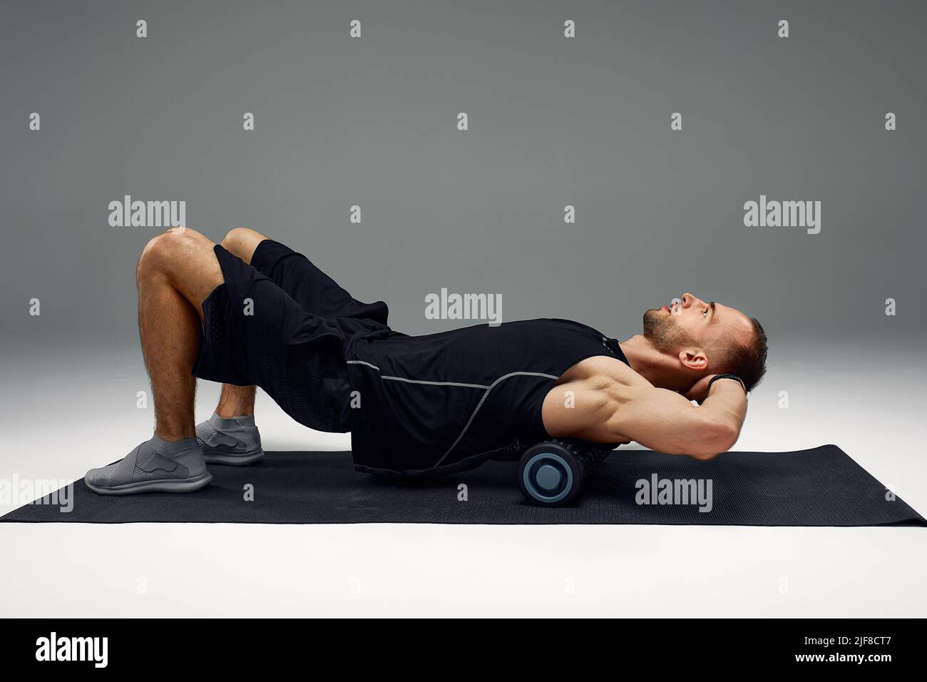 Athletic man using a foam roller to relieve sore muscles after a