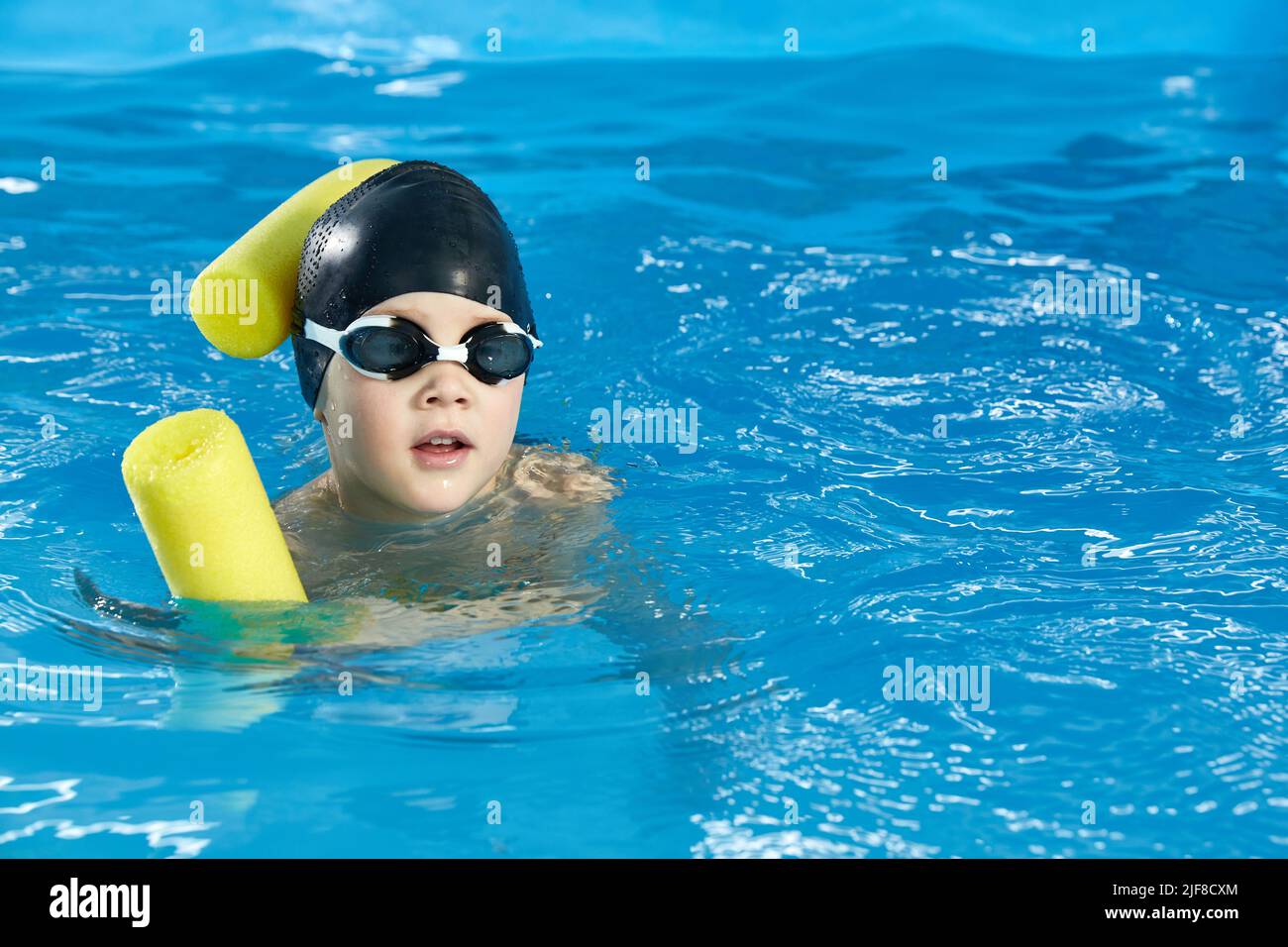 Preschool boy learning to swim in pool with foam noodle Stock Photo Alamy