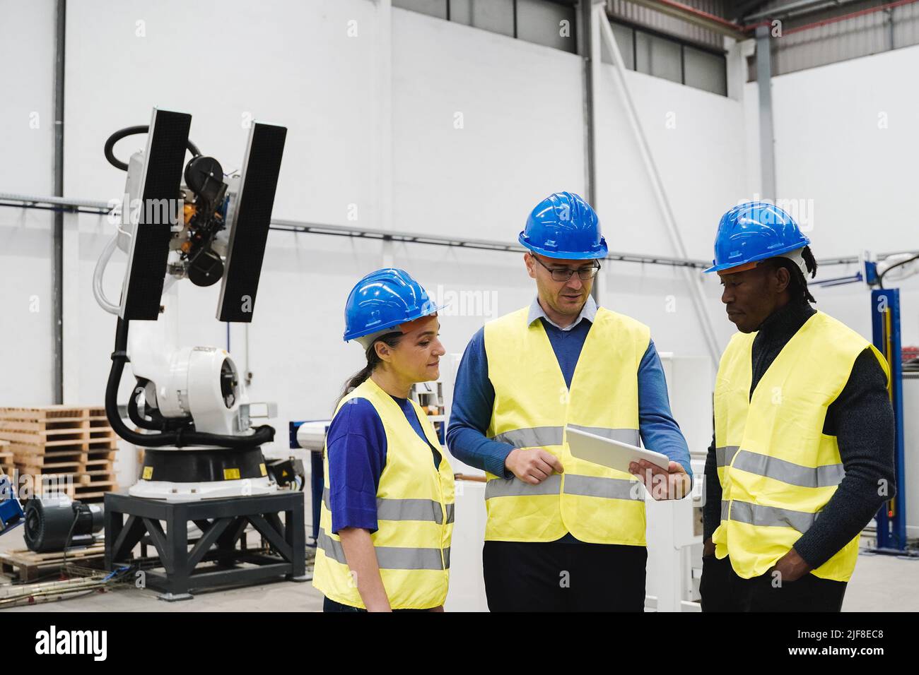 Industrial engineers working with automated arm robot inside AI robotic production factory - New technology concept - Focus on senior woman face Stock Photo