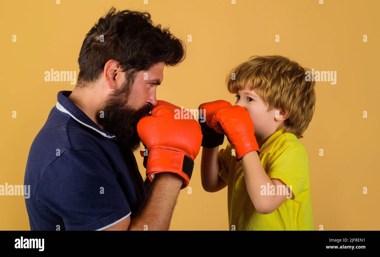 Child boy in boxing gloves training with coach. Punching knockout. Father and son in sportswear. Stock Photo