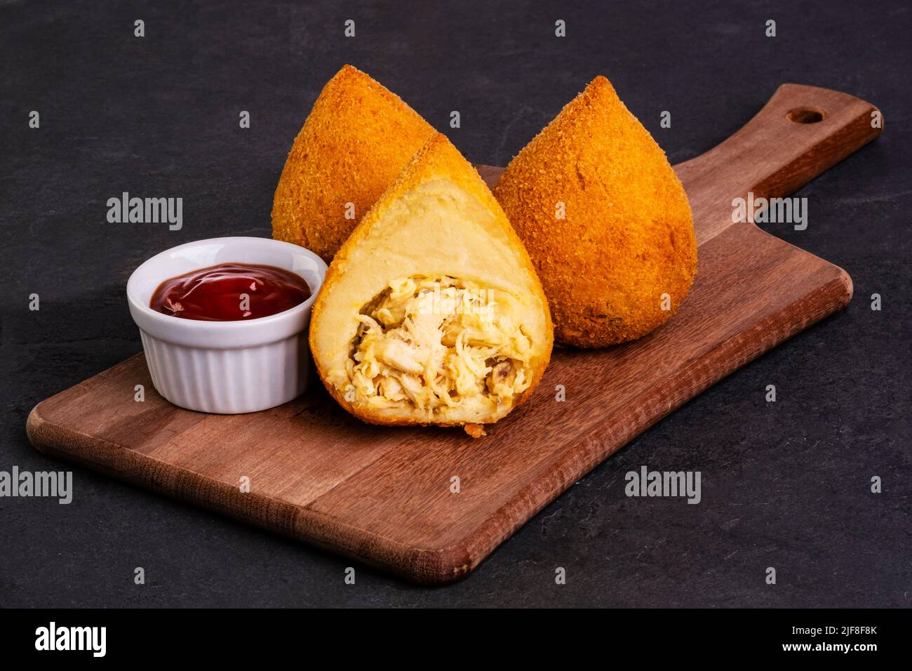 traditional fried coxinha on a wooden board over slate stone. Stock Photo