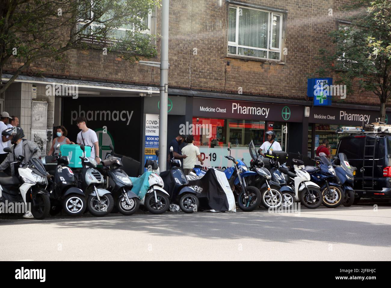 Scooters and Mororcycles Parked on Road Outside Pharmacy and Covid-19 Vaccination Centre Kings Road London England Stock Photo