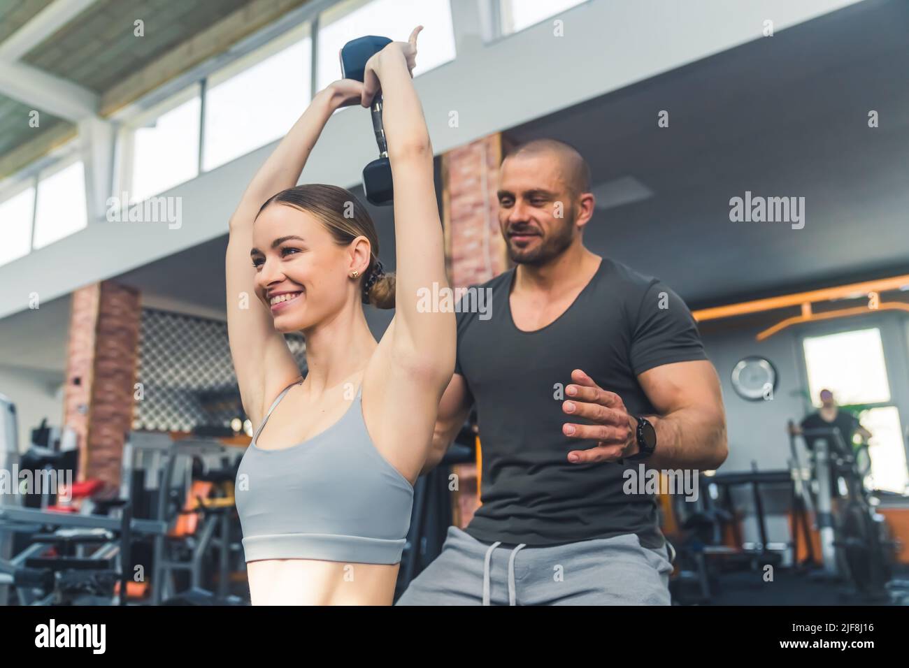 Athlete slim pretty girl lifting a dumbbell above her head being