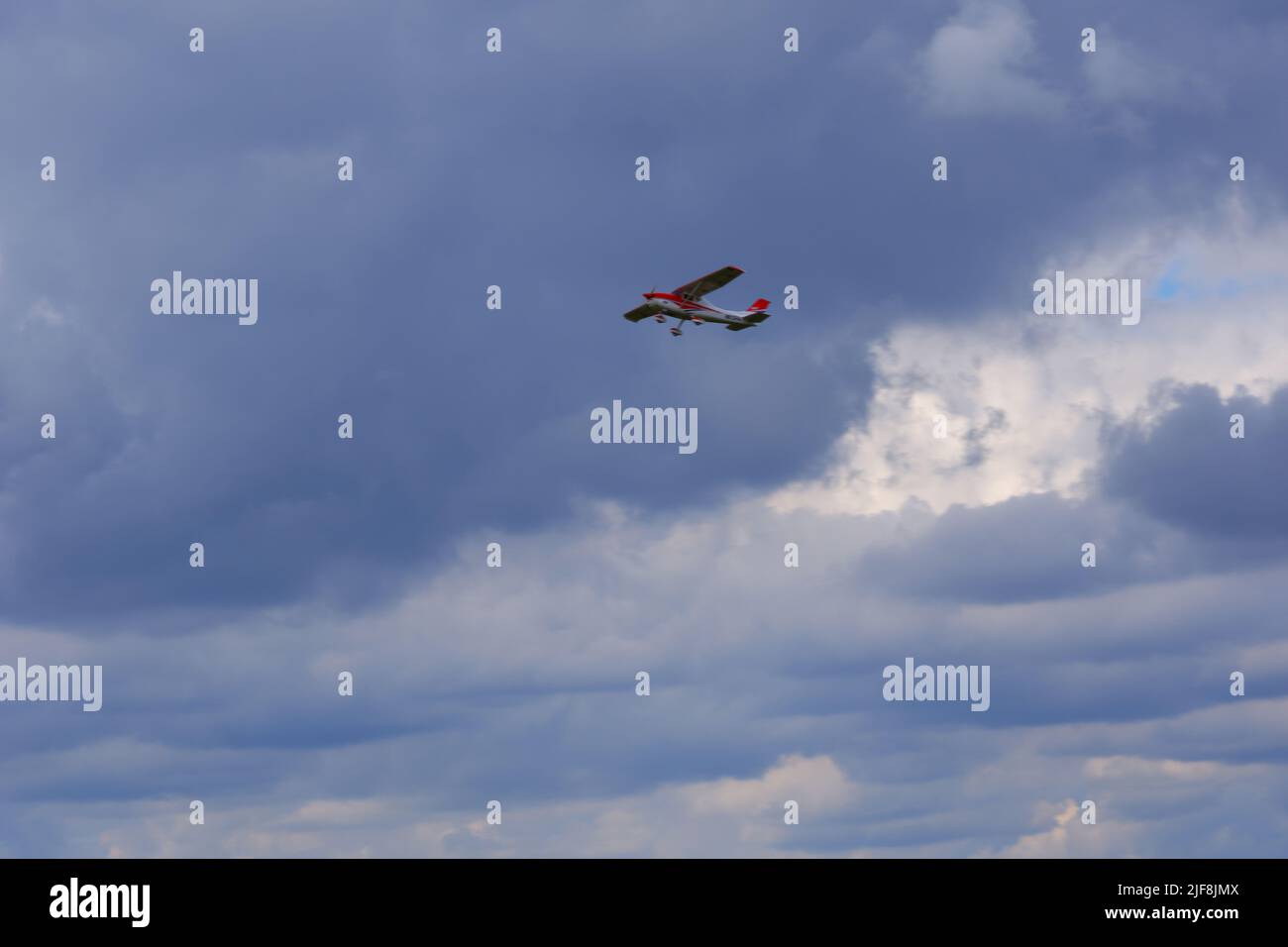Small airplane flying within dark clouds Stock Photo