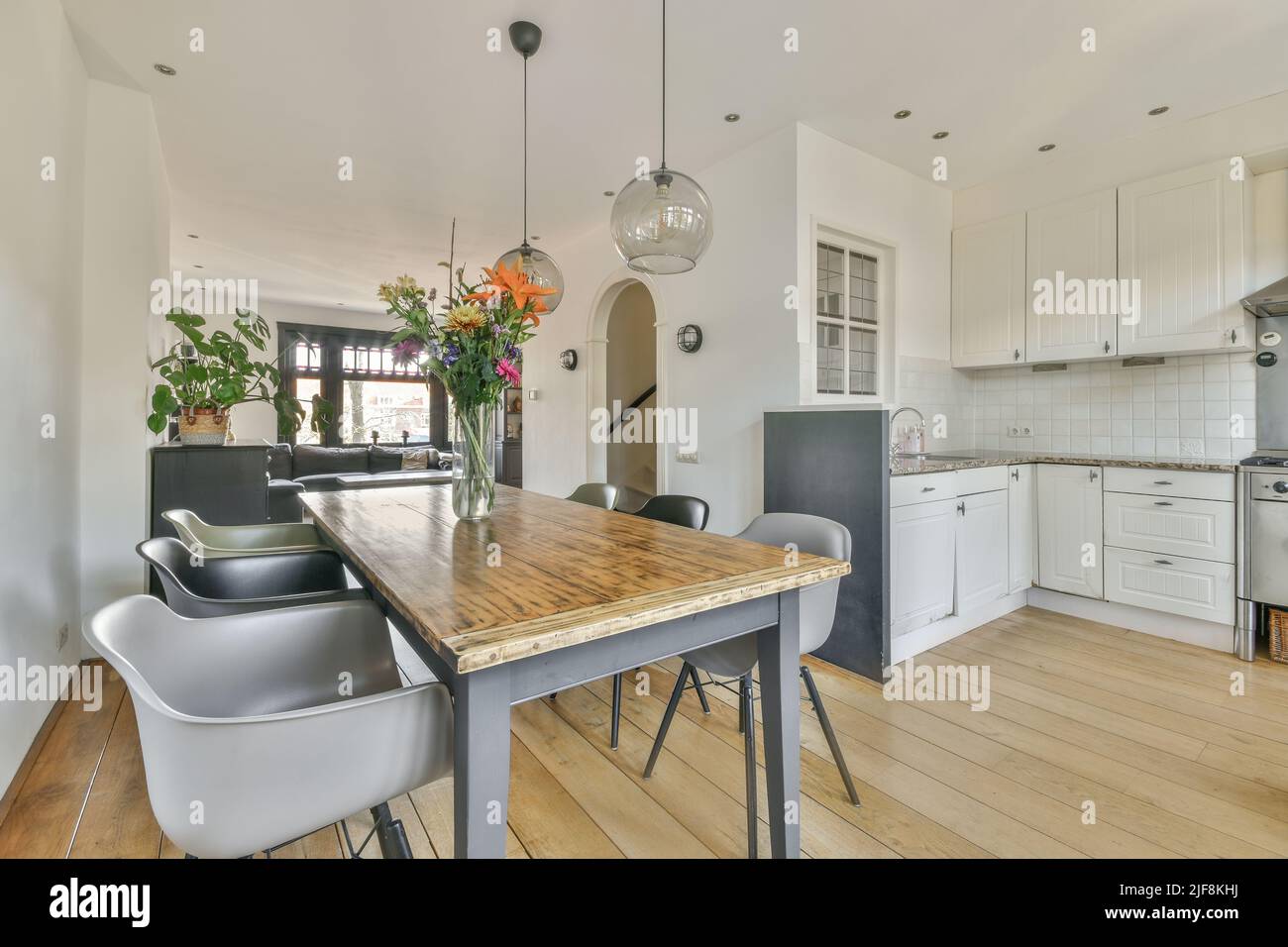 Wooden table with vase of flowers under glass pendant lamp in modern