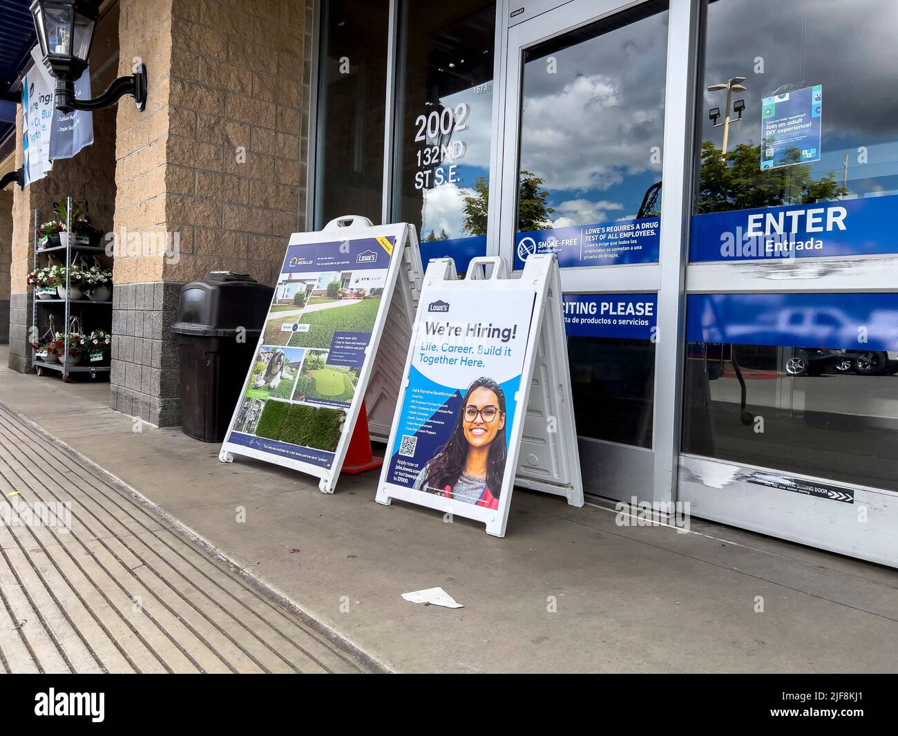 Mill Creek, WA USA - circa June 2022: Angled view of a Now Hiring sign outside of the entrance to Lowe's home improvement store. Stock Photo