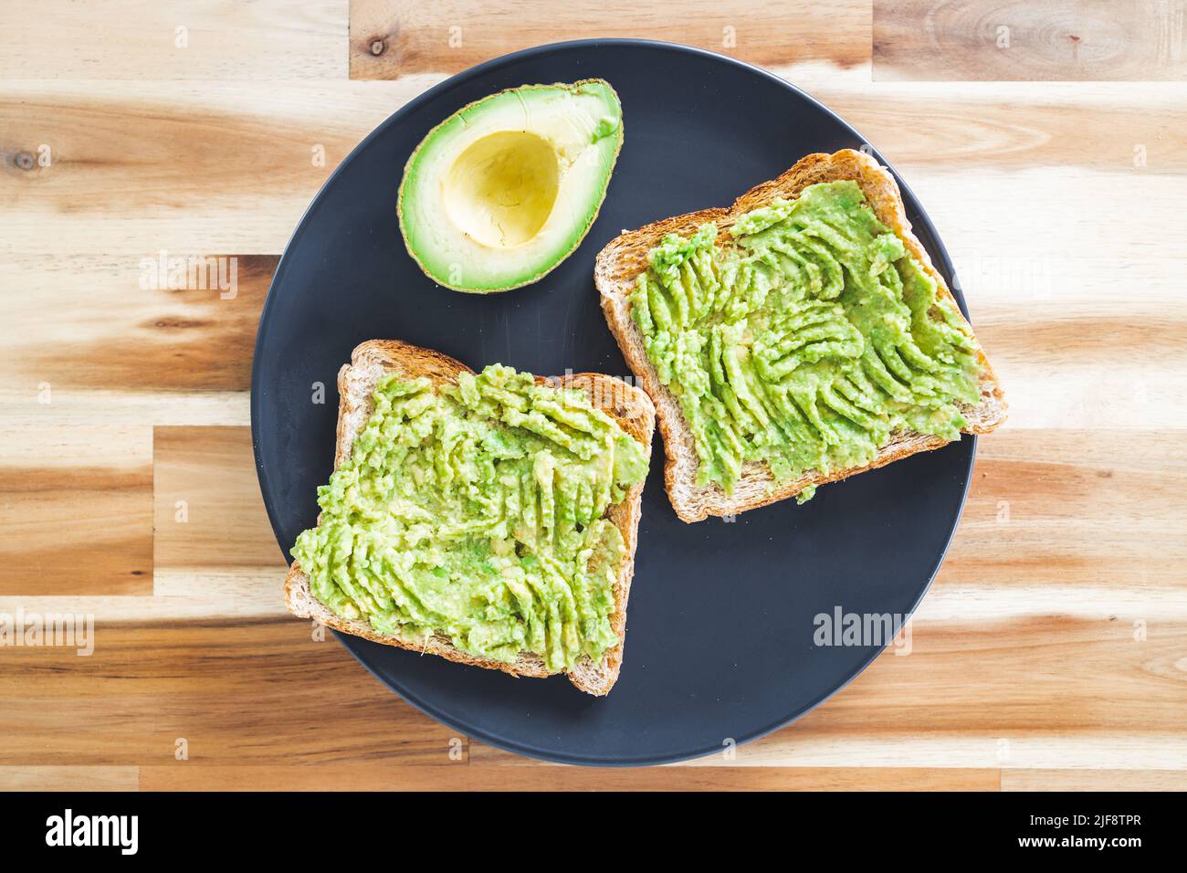 basic plantbased smashed avocado toast with half avocado next to it