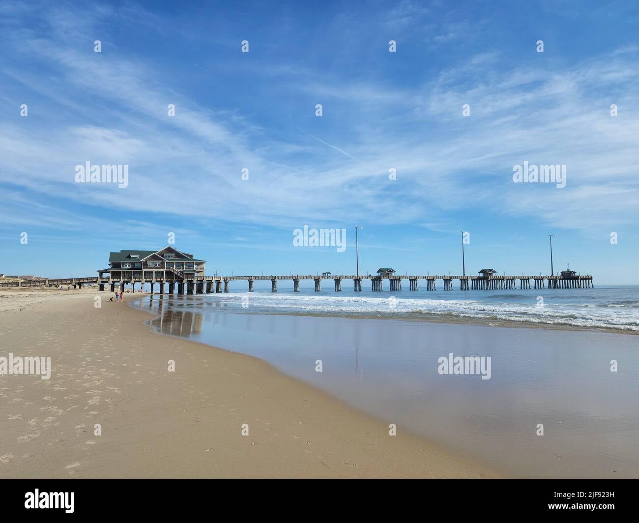 People on Nags Head Beach with the fishing pier, Jennette's Pier in the background. Photographed in Outer Banks, North Carolina. Image has copy space. Stock Photo