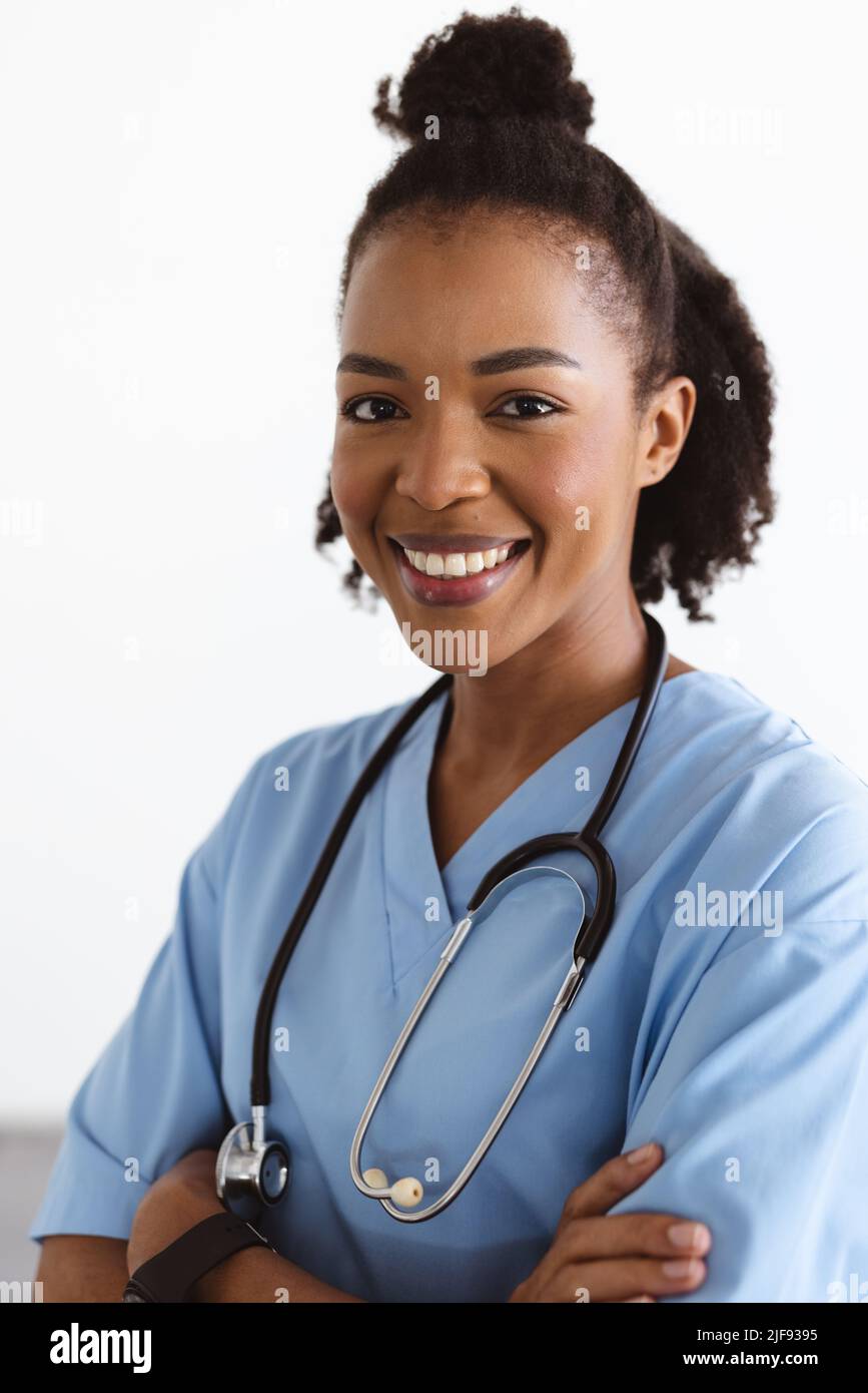 Close-up portrait of smiling african american young female doctor with afro hair against white wall Stock Photo