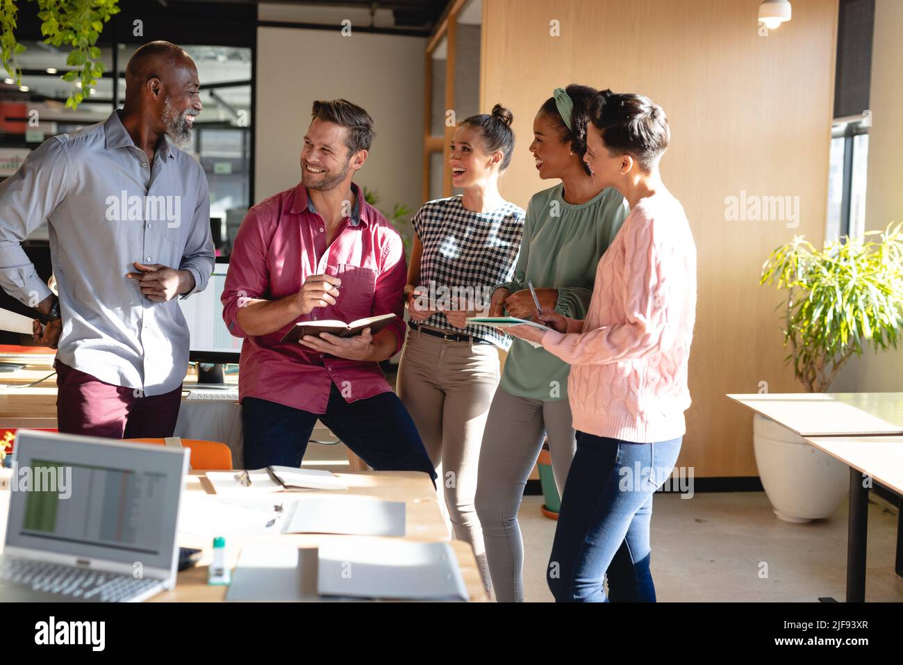 Happy multiracial male and female colleagues discussing in meeting at ...