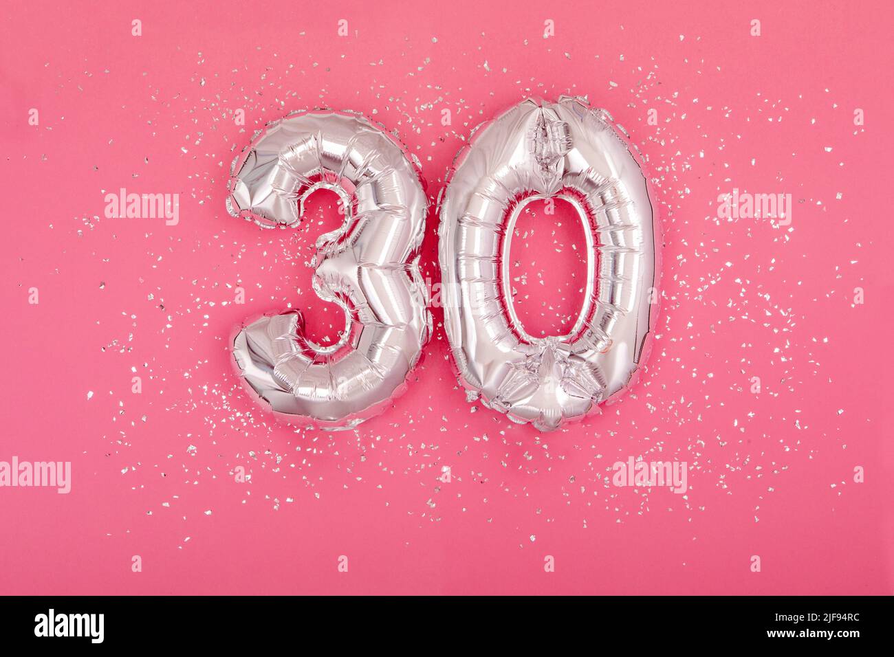 Silver balloon in shape of number thirty 30 pink background Stock Photo