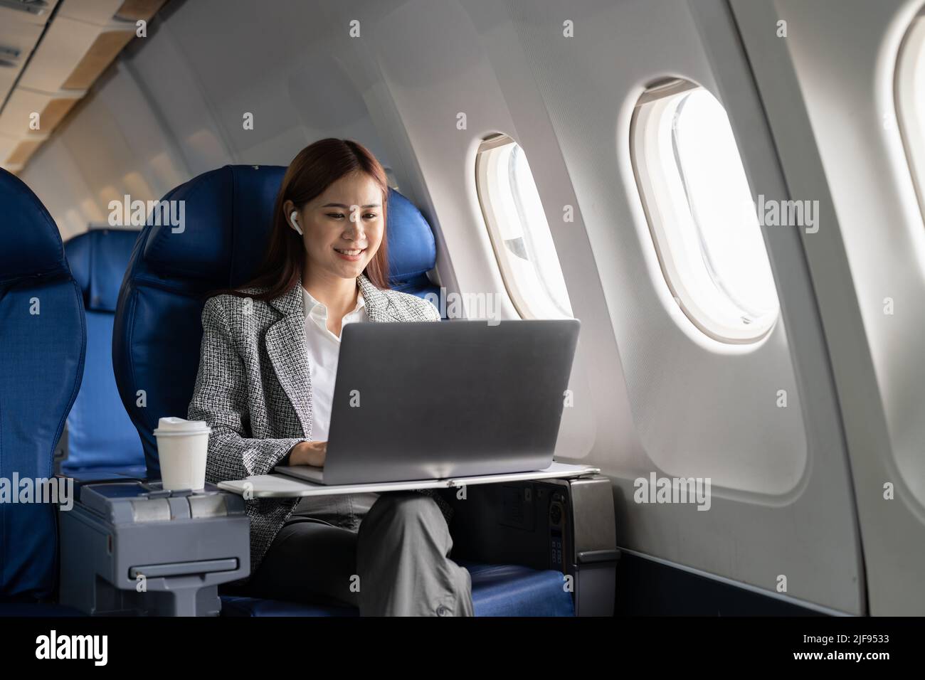 business asian woman using laptop while flying on airplane near window. Stock Photo
