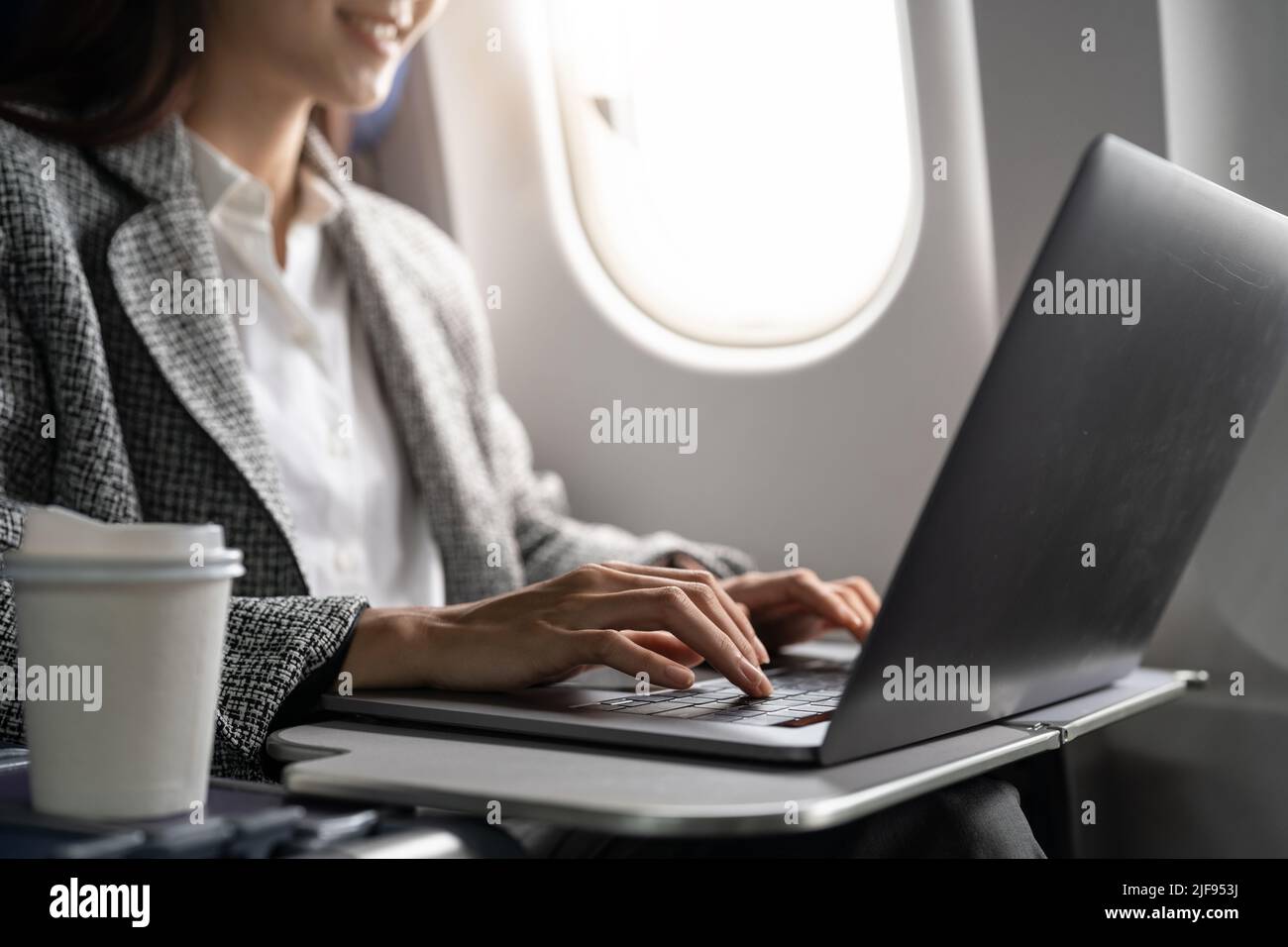 Close up hand of business asian woman uses laptop while flying on airplane near window. Stock Photo