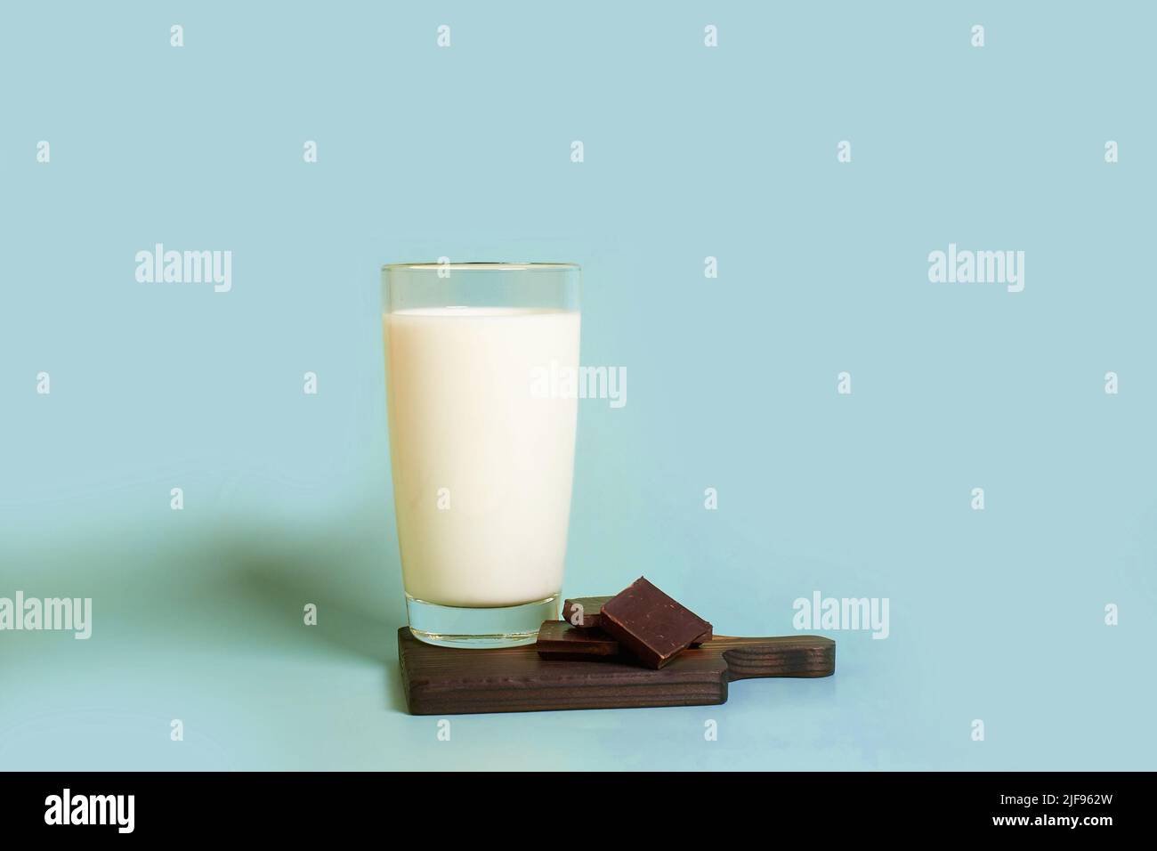 A glass of milk and pieces of dark chocolate on a wooden stand  Stock Photo