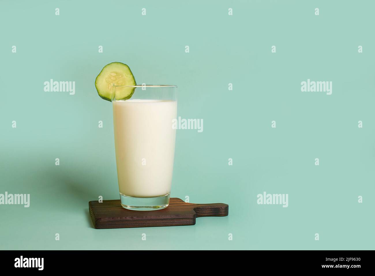 Glass with milk and cucumber slice on a wooden stand  Stock Photo