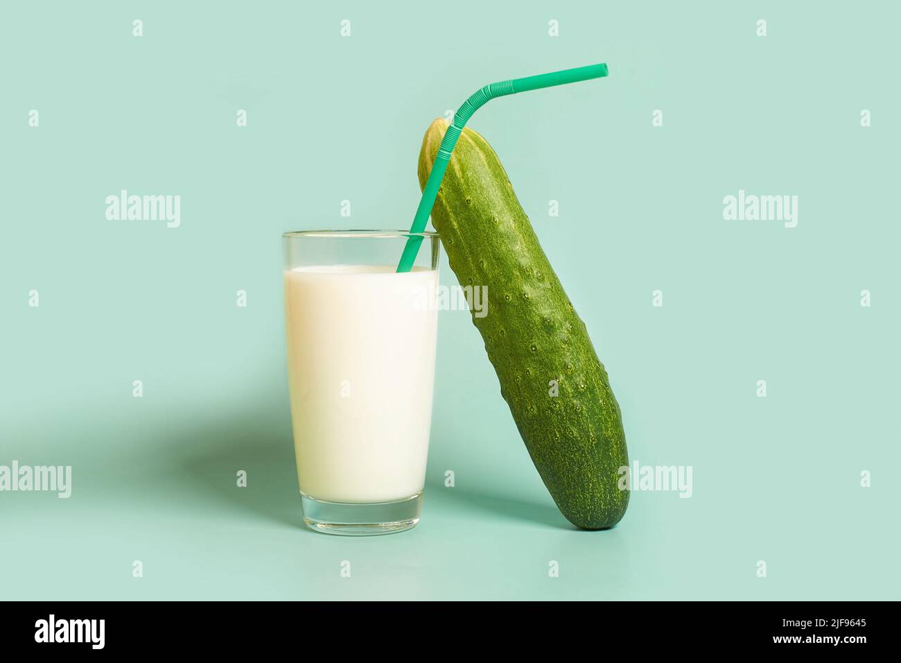 Glass with milk, plastic tube and cucumber  Stock Photo