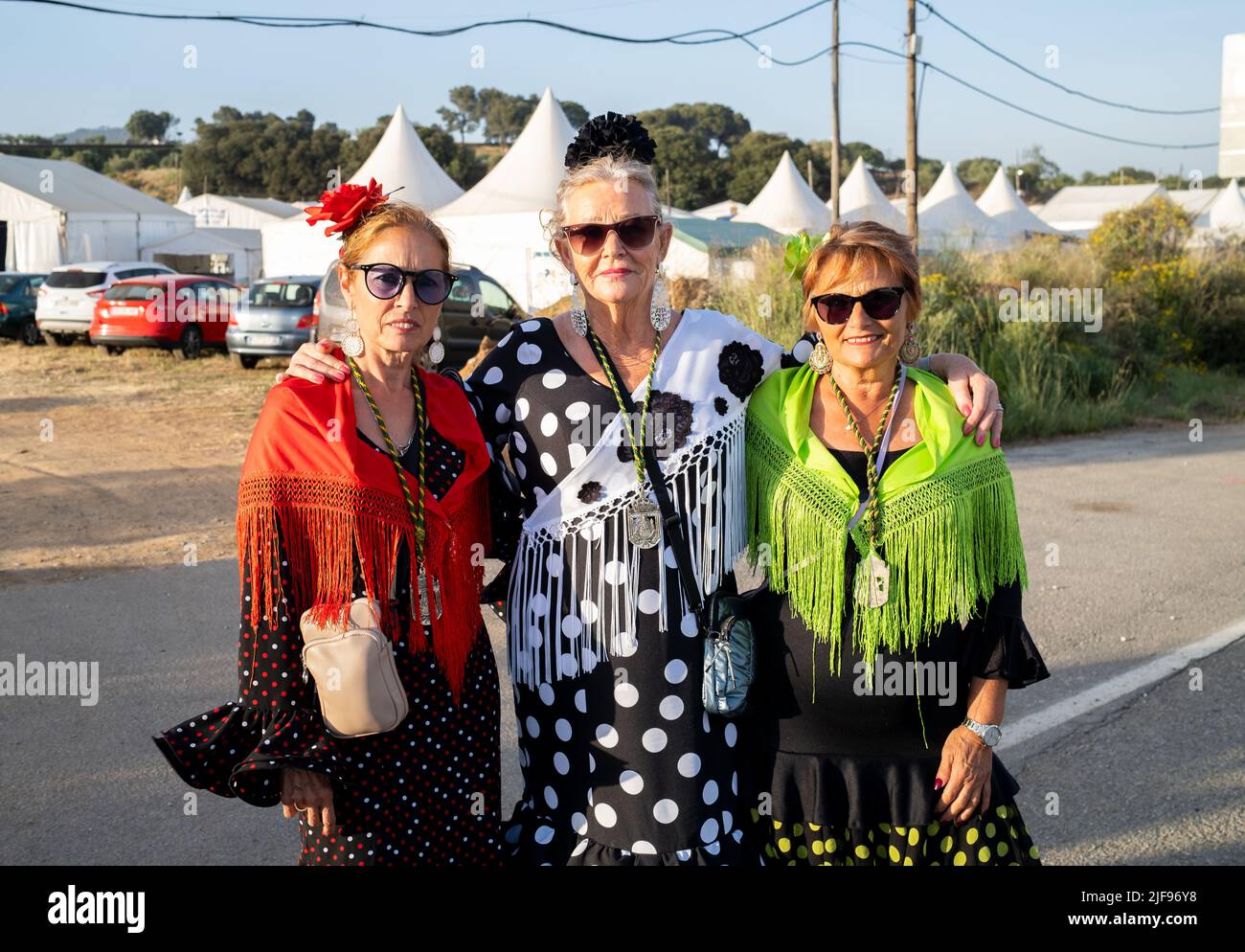 Barcelona, Catalonia, Spain, July 4, 2022: Three women with modern sunglasses between 60 and 70 years old wear classic flamenco dresses, contrast of t Stock Photo