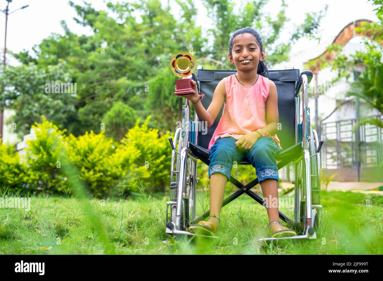 concpe tof inspiration and motivation, showing by young teenager girl kid with disability celebrating by holding trophy on wheelchair Stock Photo