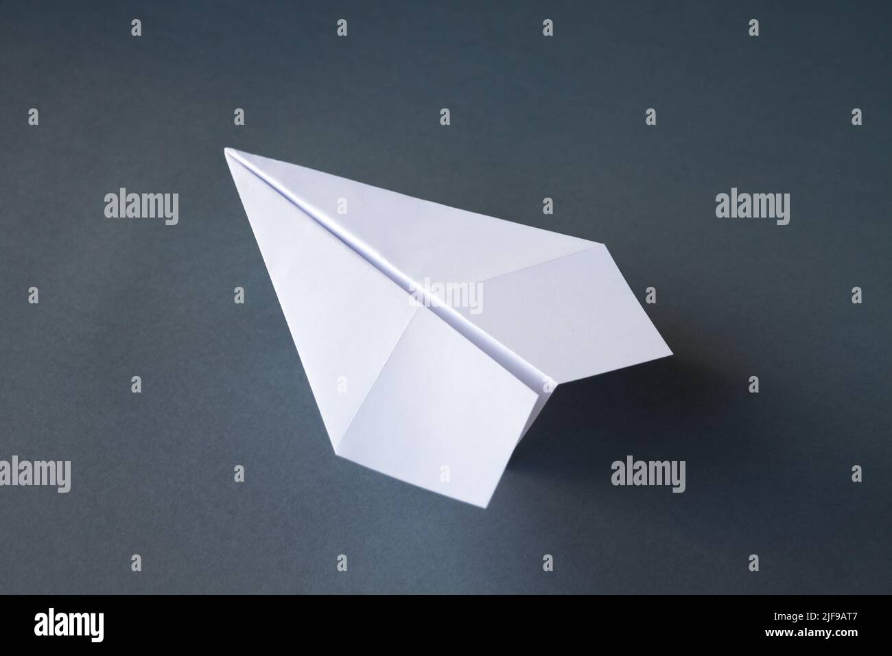 White paper plane origami isolated on a blank grey background Stock Photo