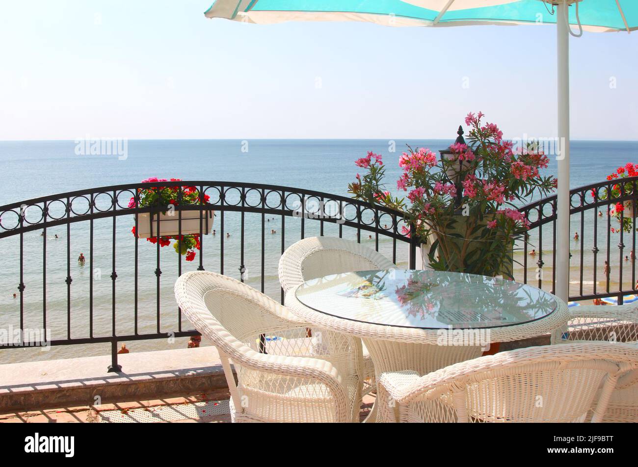 Cozy veranda next to the beach with wicker furniture and an umbrella. Nessebar, Bulgaria Stock Photo