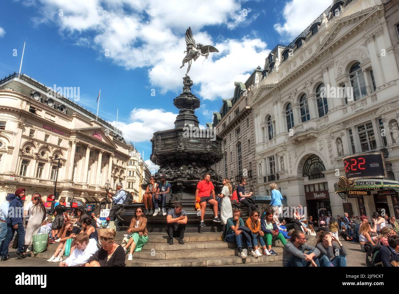 London, United Kingdom, June 28th 2022 Tourists sitting on the steps of the Shaftesbury Memorial Fountain and statue of Greek god Anteros, Piccadilly Stock Photo