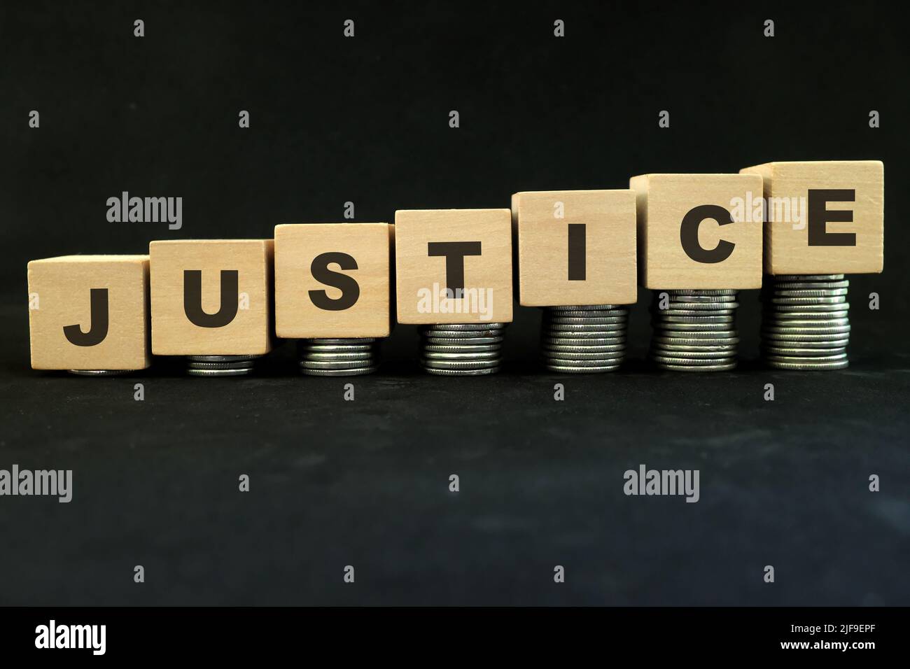 High price of justice, inequality and justice for the rich only concept. Wooden blocks with increasing stack of coins in dark black background. Stock Photo