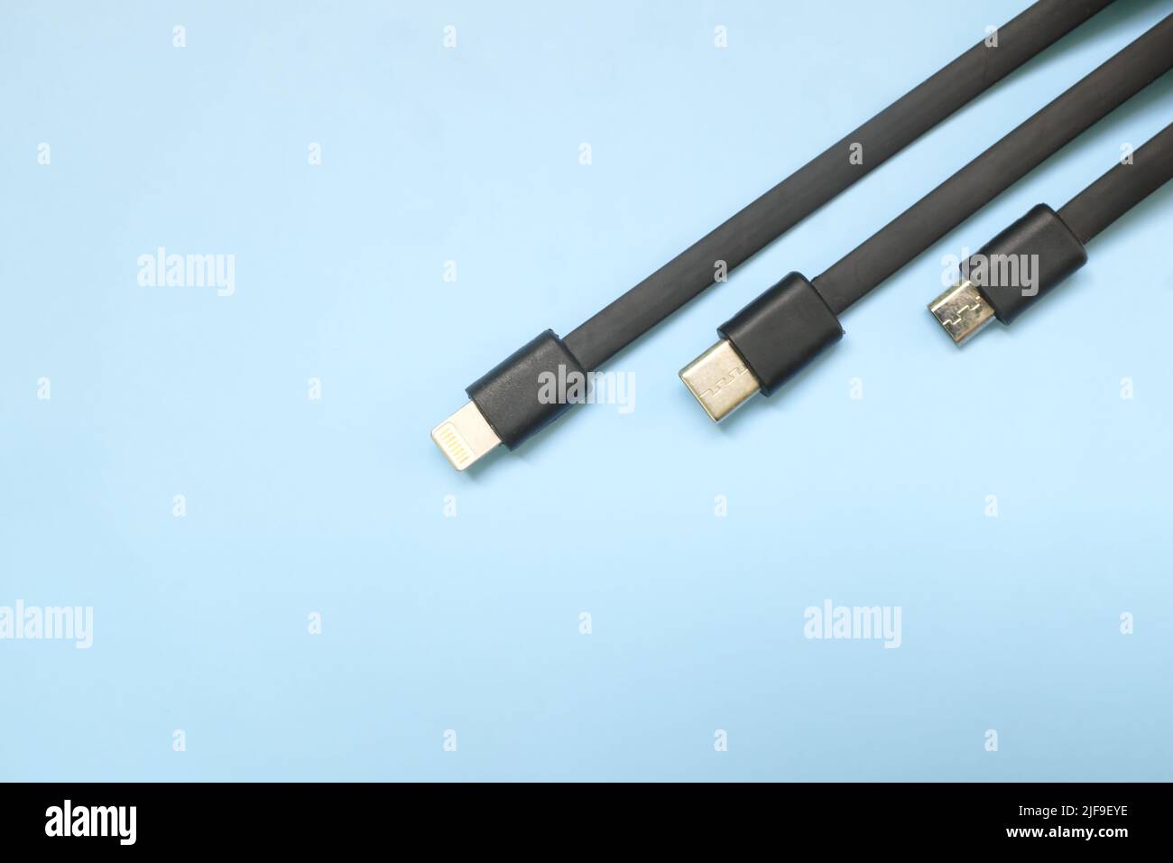 Smartphone or mobile phone standard charging cable plugs flat lay. Micro USB, type c and lightning cable in blue background with copy space. Stock Photo