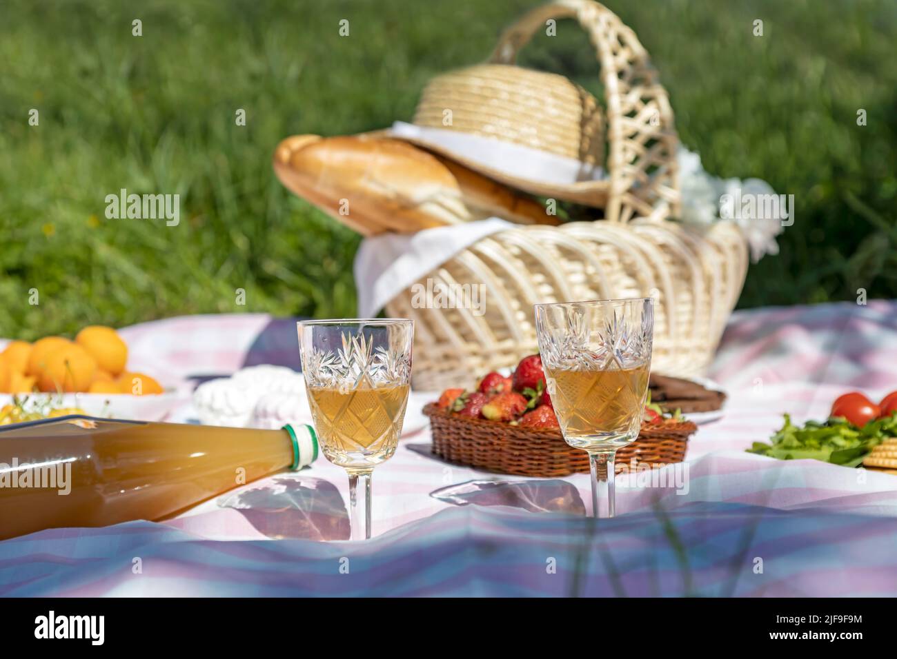 Picnic in the park, white wine in glasses, and baguettes in a basket. Stock Photo