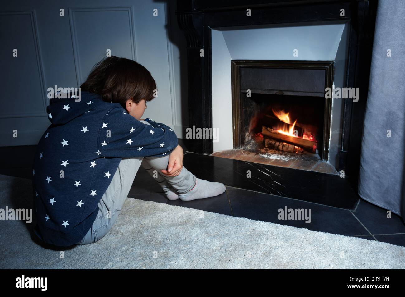 Boy sit in front of the home fireplace look at fire Stock Photo Alamy