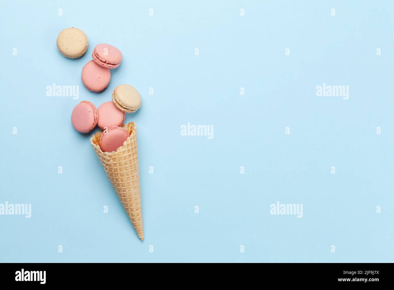 Various macaroon cookies in ice cream cones. Flat lay on blue ...