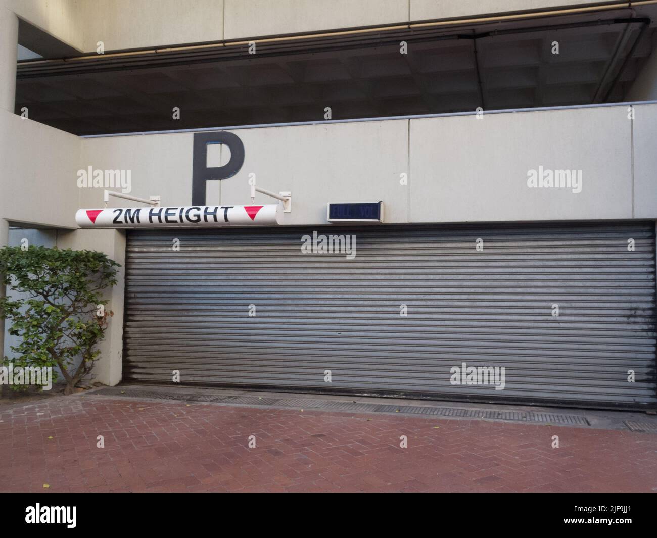 closed metal garage door at a parking garage with a maximum height restriction sign of 2 metres in a city building Stock Photo