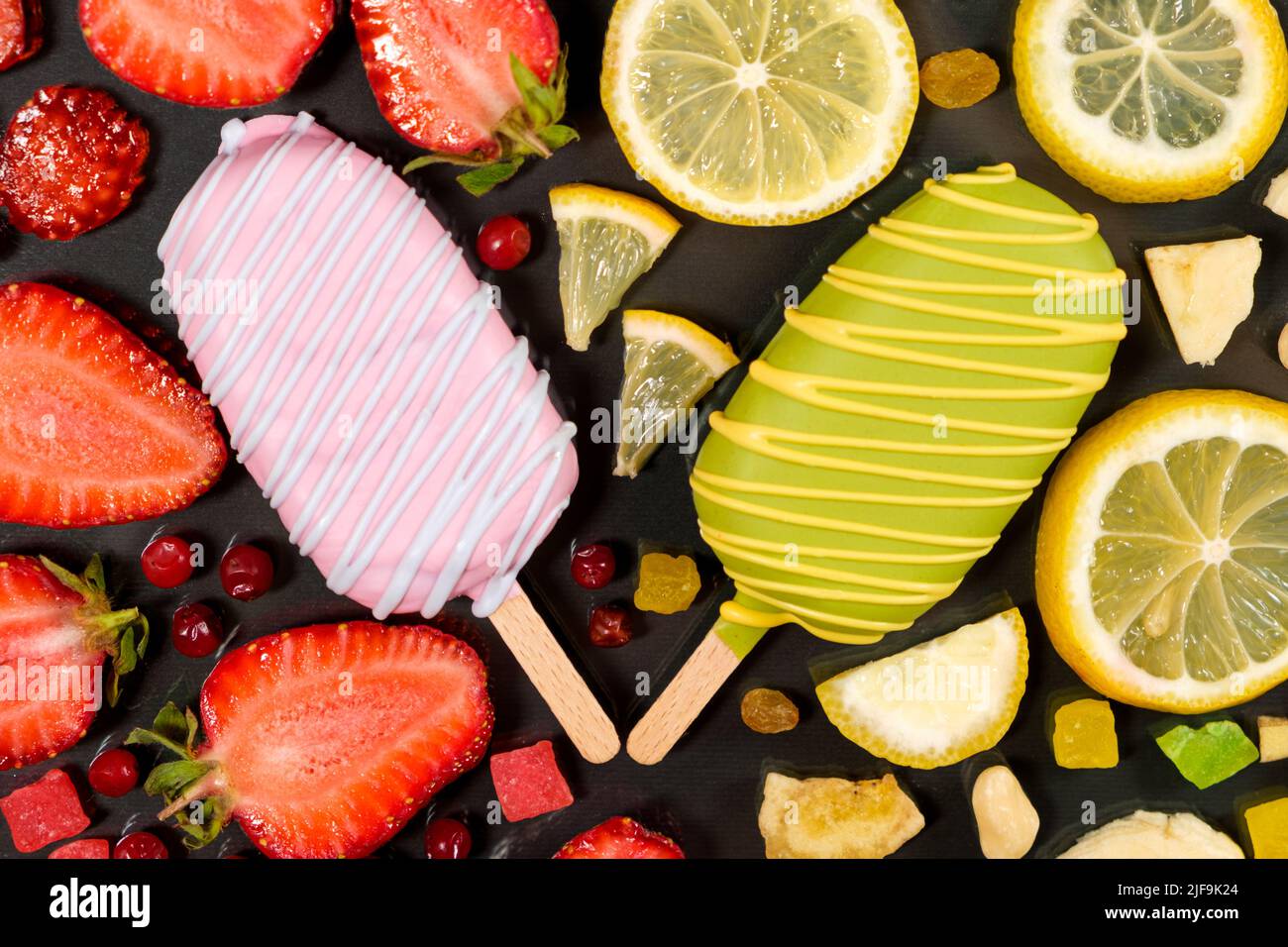 Two ice creams on a sticks - strawberry and lemon on a black background. Summer fruit desserts. Stock Photo